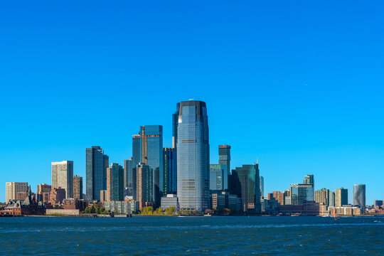 Panoramic view of the modern Jersey City skyline in New Jersey as seen across the open water of New York Bay, featuring prominent downtown skyscrapers and high-rise office towers.