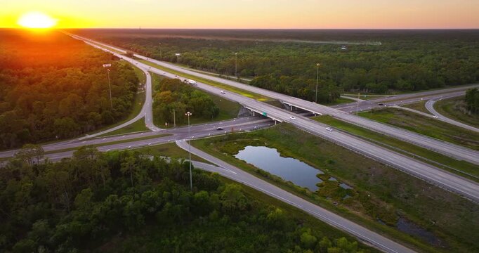 American highway bridge and exit lanes forming rural interchange with continuous vehicle movement at sunset