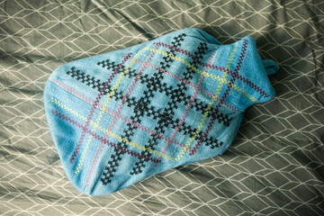 Light Blue Plaid Fleece Hot Water Bottle on Patterned Bed Sheets © Claudio Bórquez