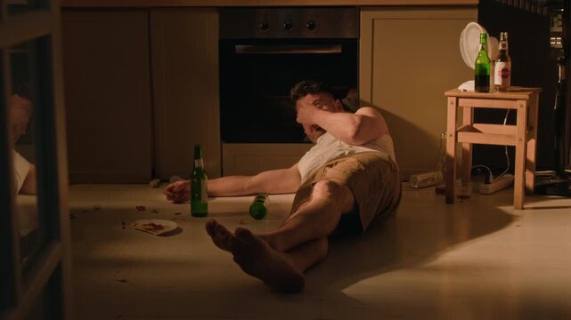 Middle aged Caucasian man waking up on floor surrounded by empty beer bottles and drinking alcohol. Clip perfect for addiction awareness campaigns and rehabilitation projects