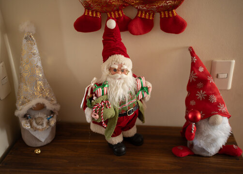 Santa Claus Figurine Flanked by Christmas Gnomes on Wooden Shelf