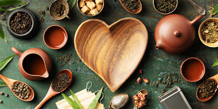Heart-Shaped Bowl with Teaware and Tea Leaves on Rustic Background