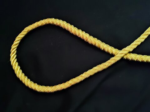 Close up of shiny gold metallic rope for decorative border,  isolated on a black background