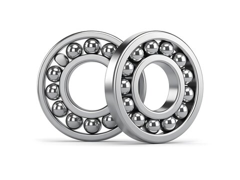 Metallic ball bearings stand aligned together over white surface.