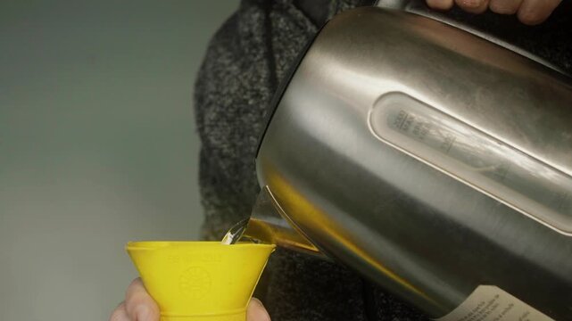 Close up view of a hand carefully filling a rubber hot water bottle