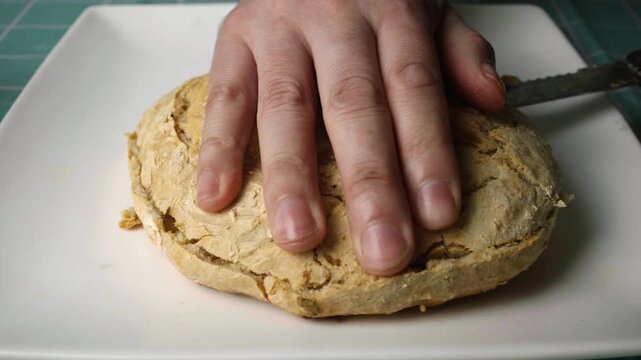 Close up view of hands slicing open a fresh rustic homemade bread piece