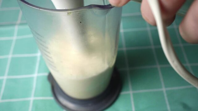 Close up view of hands blending ingredients to make fresh homemade mayonnaise