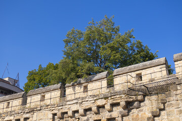 Historic defensive stone wall with elevated walkway beneath clear blue sky © gicku91