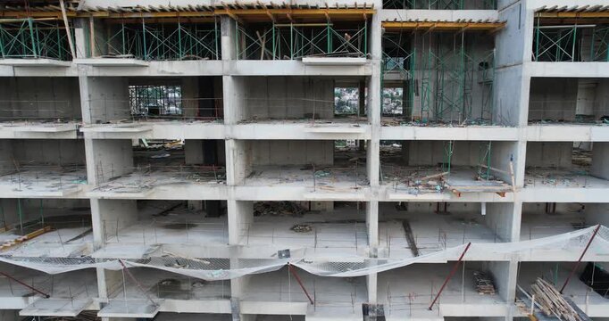 A building under construction with scaffolding and a tarp covering the top. The building is tall and has many windows