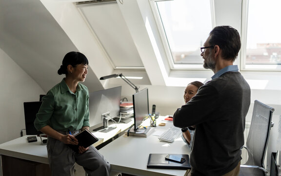 Business colleagues talking informally in the office, representing professional networking, workplace communication and positive working relationships