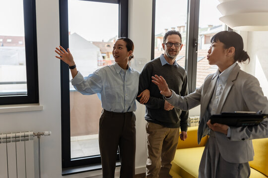 Professional real estate agent giving prospective buyers a guided tour of a modern apartment and explaining property features.