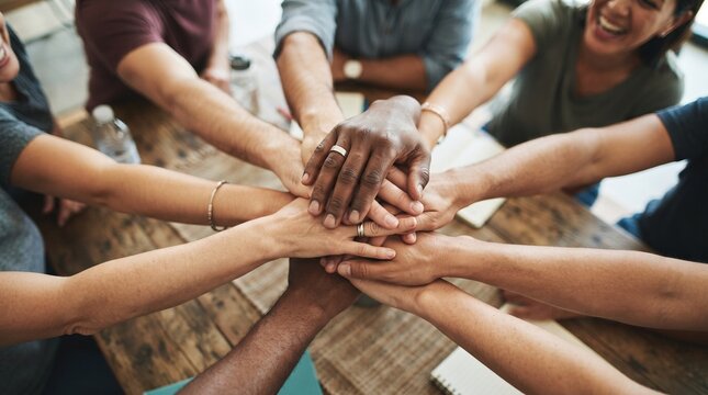 Diverse group of people stacking hands together for teamwork and unity in a meeting.