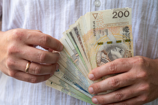 Close up of Man Hands Holding Fan of Polish Zloty Banknotes for Income and Savings Concept