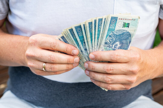 Close up of Man Hands Holding Fan of Polish 50 Zloty Banknotes for Salary and Income Concept
