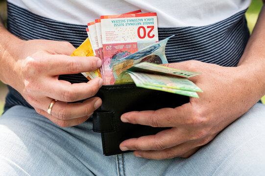Close up of Man Hands Holding Open Wallet and Swiss Francs Banknotes Stack for Budget Concept
