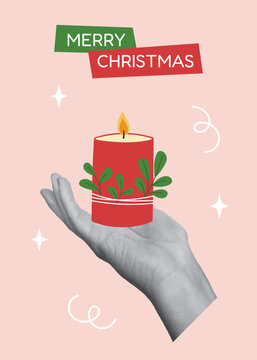 Christmas greeting card template. Hand holding burning red Christmas candle with green leaves on pastel pink background