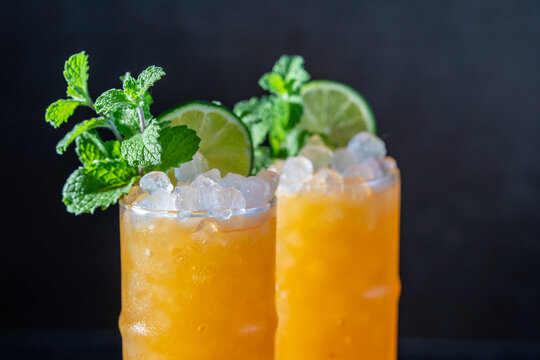 Passionfruit cocktail with mint and lime garnish on a dark surface 