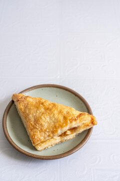 Apple turnovers on a plate with a white tile surface 