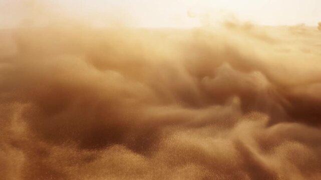 Aerial slow motion tracking pan of sand and dust clouds rolling over desert dunes at sunrise with golden hazy light