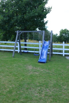 Children&rsquo;s swing set with slide in a green backyard garden