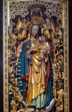 A polychrome wooden statue depicts the Virgin Mary holding child Jesus surrounded by carved angels.