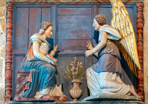 Polychrome wooden relief sculpture depicts the Annunciation scene with Archangel Gabriel and the Virgin Mary.