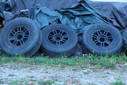 Stacked used car tires and wheels stored outdoors