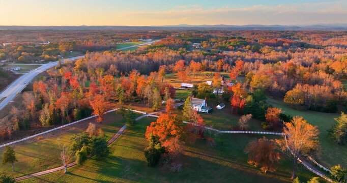 Elegant farmhouses hidden between bright autumn trees, golden leaves framing property in peaceful southern rural scene.