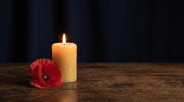 Memorial candle with a red poppy flower on a rustic wooden table