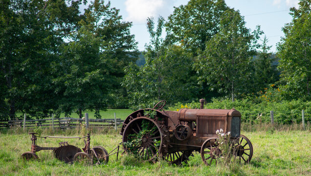 A rusty old tractor and cultivator long since retired