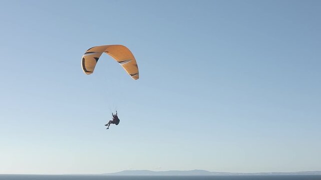 Paraglider flying above ocean horizon in cinematic slow motion aerial adventure
