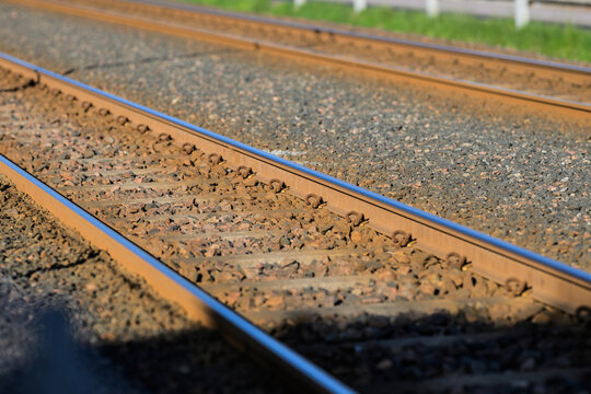 Parallel railway tracks stretching through gravel in warm light.