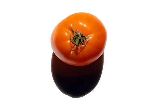 Flat lay top view of a orange tomato on a white background with a shadow. Focus on healthy food, citrus, vitamins, and diet concepts.