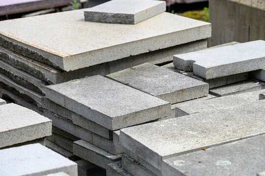 Stacked gray stone slabs prepared for construction reuse.