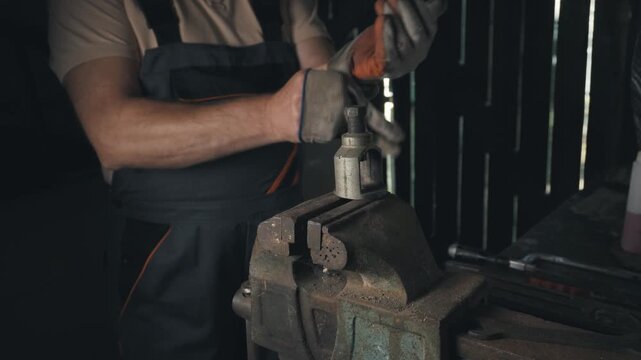 Skilled technician in workwear adjusts a metal component using a vice grip in a workshop, showcasing the detailed process of precision craftsmanship in a rustic setting with tools visible