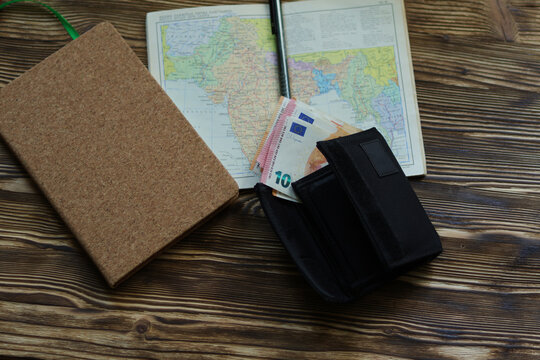 Travel planning flat lay with map, notebook, wallet, and Euro cash on wooden table
