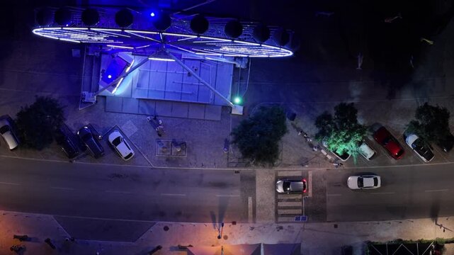 Aerial night view of Set&uacute;bal, Portugal, showcasing the illuminated city, waterfront, Ferris wheel, streets, harbor, boats and coastline. Cinematic nighttime cityscape overlooking the Sado Estuary and