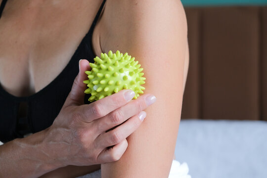 Woman massaging her neck with a trigger point ball for pain relief and wellness