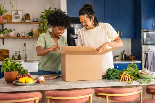 Young couple unpacking blank meal kit box in modern kitchen