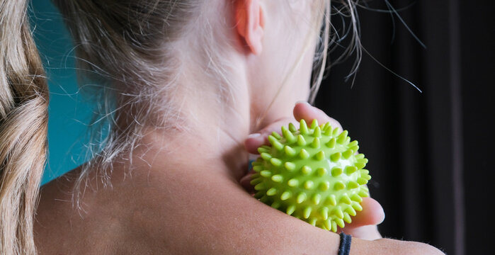 Woman massaging her neck with a trigger point ball for pain relief and wellness