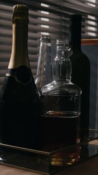 Vertical video of various alcohol bottles including whiskey decanter and wine standing on tray. Footage suitable for addiction awareness campaigns or beverage industry marketing