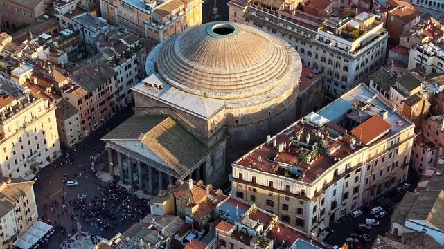 Aerial drone view of the round dome of the Pantheon and the small square in front of it among narrow streets and orange rooftops, Rome, Italy