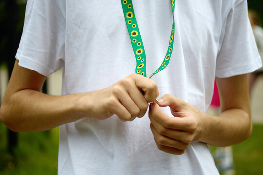 Person's hands adjusting a green lanyard with sunflower pattern