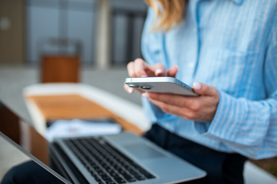 Businesswoman using smartphone and laptop in coworking space