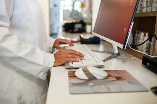 Pharmacist typing on computer at pharmacy counter