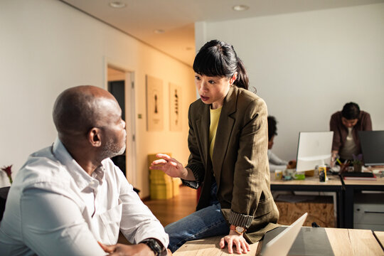 Coworkers discussing project in modern open office