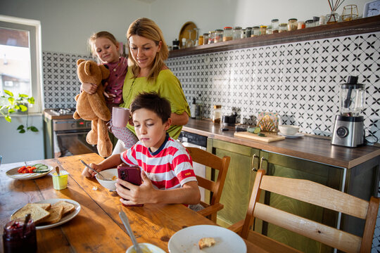 Mother with children at breakfast in home kitchen