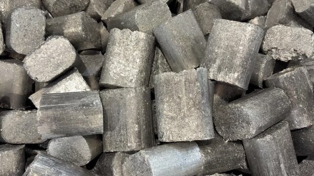 Pulling out from a heap of Aluminium pucks, compressed aluminium shavings from an industrial lathe or CNC machine, to be recycled