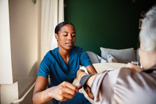 Nurse checking senior's blood pressure at home