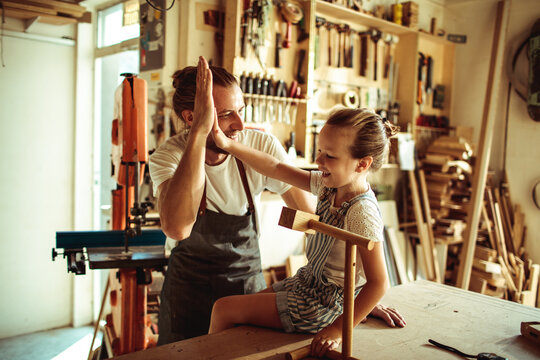 Father and daughter high five in woodworking shop